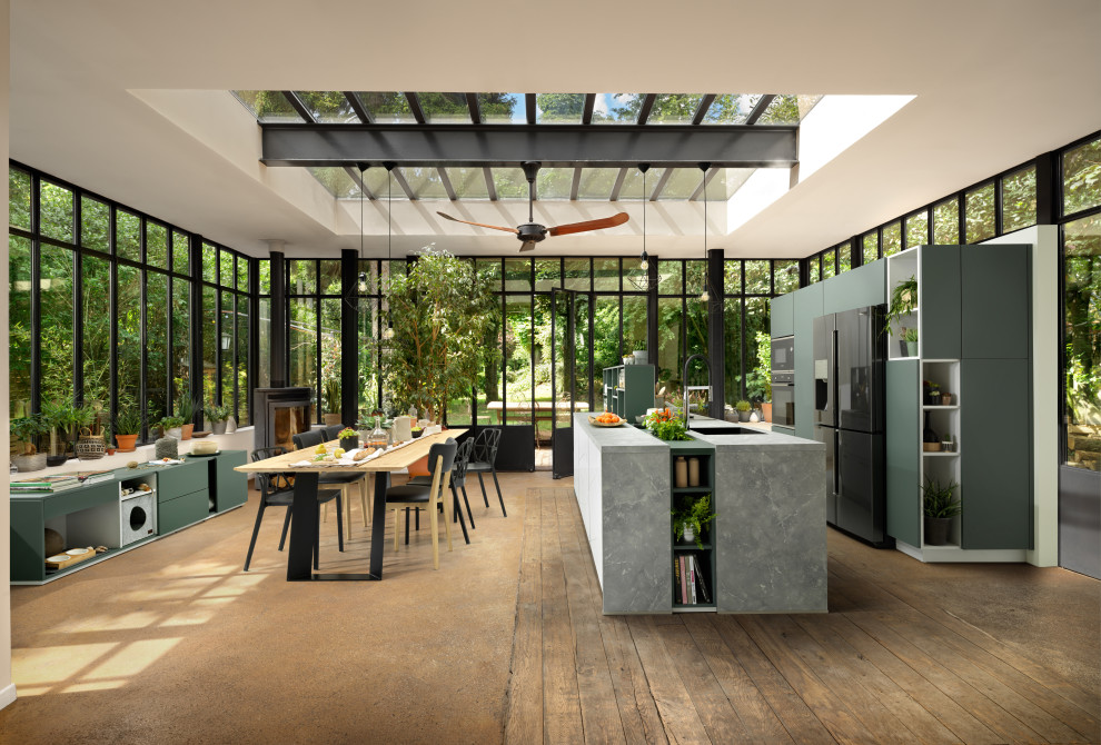 На фото: большая прямая кухня в стиле модернизм с обеденным столом, одинарной мойкой, плоскими фасадами, зелеными фасадами, столешницей из ламината, черной техникой, островом и серой столешницей с