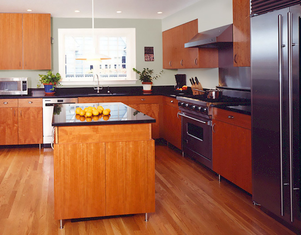 Photo of a large modern l-shaped enclosed kitchen in DC Metro with a submerged sink, flat-panel cabinets, light wood cabinets, composite countertops, metallic splashback, metal splashback, stainless steel appliances, light hardwood flooring, an island and brown floors.