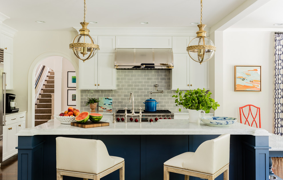 Diseño de cocina comedor clásica renovada con puertas de armario blancas, salpicadero verde, salpicadero de azulejos tipo metro, electrodomésticos de acero inoxidable y una isla
