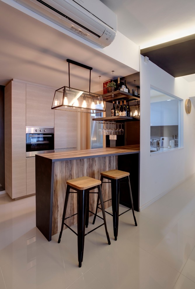 На фото: кухня в скандинавском стиле с плоскими фасадами, светлыми деревянными фасадами, деревянной столешницей, черной техникой, бежевым полом и коричневой столешницей