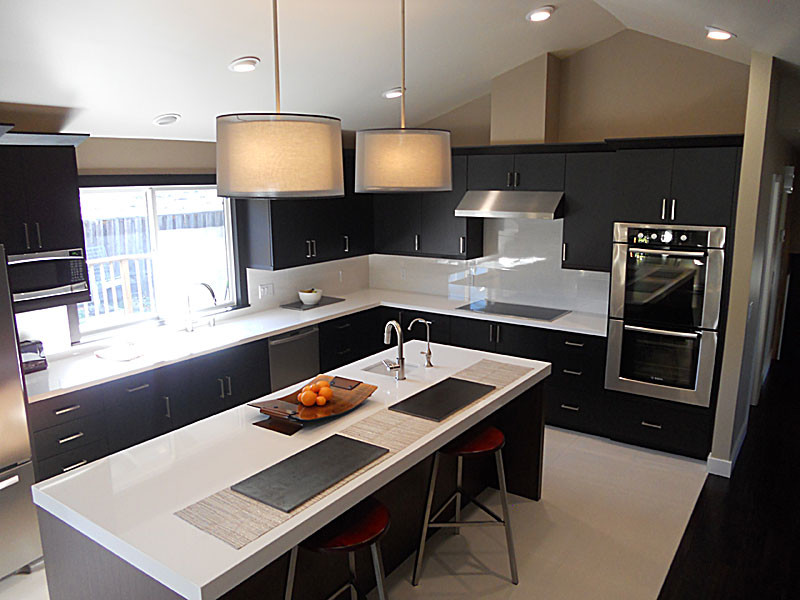 Photo of a medium sized contemporary l-shaped kitchen/diner in San Francisco with a submerged sink, flat-panel cabinets, black cabinets, engineered stone countertops, white splashback, glass sheet splashback, stainless steel appliances, porcelain flooring and an island.
