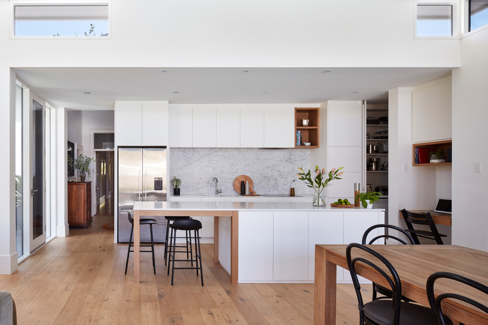 Zweizeilige Moderne Wohnküche mit Unterbauwaschbecken, flächenbündigen Schrankfronten, weißen Schränken, braunem Holzboden, Kücheninsel, braunem Boden und weißer Arbeitsplatte in Adelaide