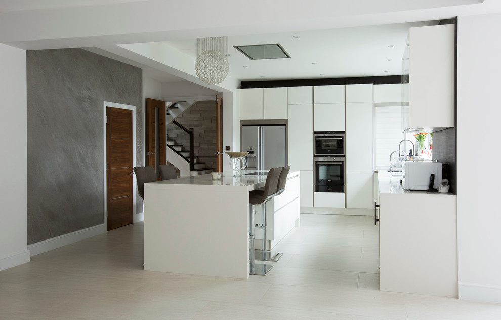 Cette image montre une cuisine design avec un évier encastré, un placard à porte plane, des portes de placard blanches, un électroménager en acier inoxydable et îlot.