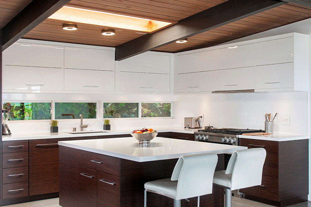 Medium sized retro l-shaped kitchen in San Diego with flat-panel cabinets, composite countertops, white splashback, stainless steel appliances, an island, a submerged sink and white cabinets.