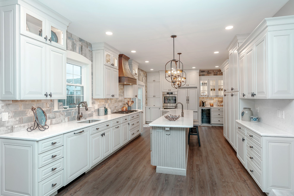 Idéer för att renovera ett vintage vit vitt kök, med en undermonterad diskho, luckor med upphöjd panel, vita skåp, flerfärgad stänkskydd, stänkskydd i tunnelbanekakel, rostfria vitvaror, mörkt trägolv, en köksö och brunt golv