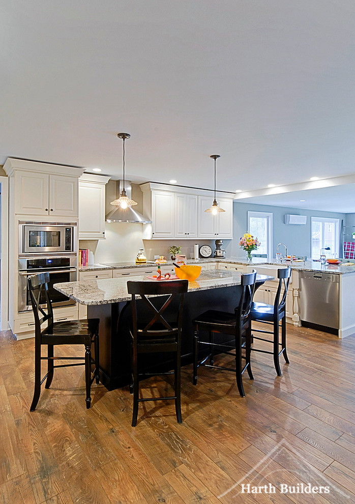 Bild på ett mellanstort lantligt l-kök, med en rustik diskho, luckor med upphöjd panel, vita skåp, granitbänkskiva, rostfria vitvaror, mellanmörkt trägolv och en köksö