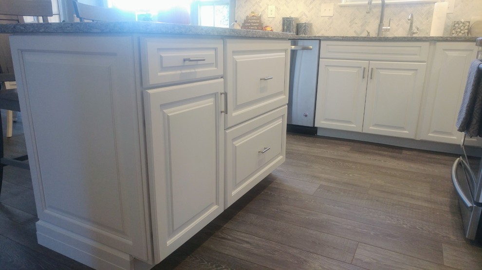 Inspiration for a mid-sized transitional l-shaped vinyl floor and gray floor eat-in kitchen remodel in Philadelphia with an undermount sink, raised-panel cabinets, white cabinets, granite countertops, gray backsplash, mosaic tile backsplash, stainless steel appliances, an island and gray countertops