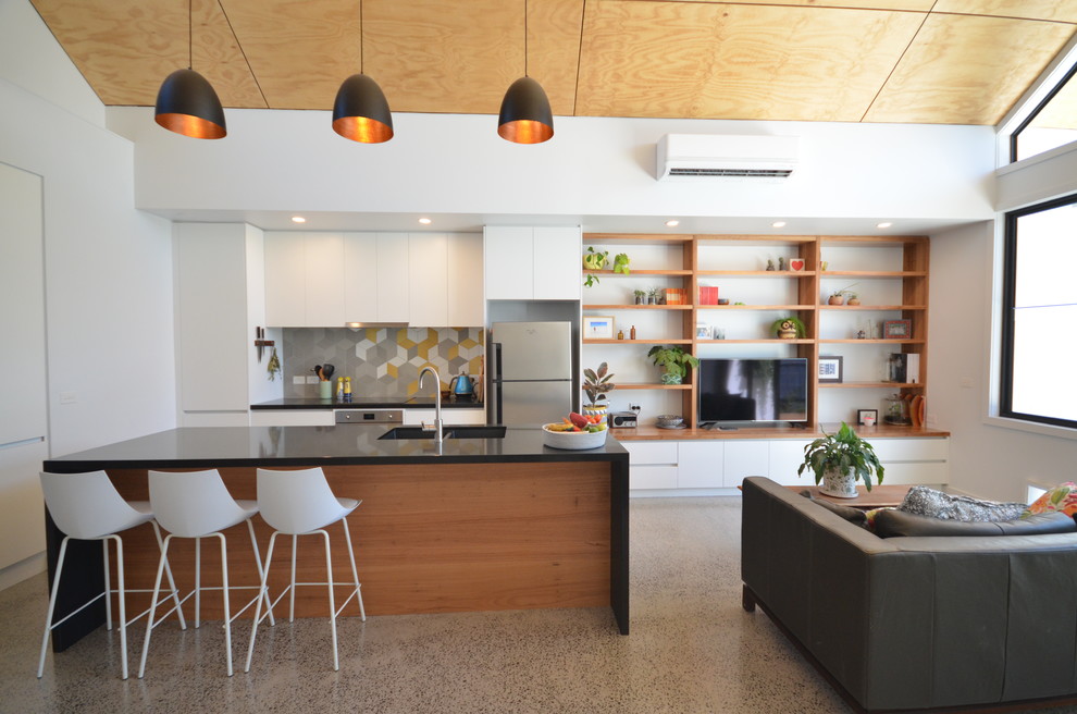 Imagen de cocina contemporánea abierta con fregadero bajoencimera, armarios con paneles lisos, puertas de armario blancas, salpicadero multicolor, electrodomésticos de acero inoxidable y una isla