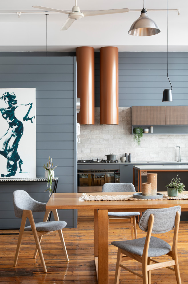 Foto på ett mellanstort funkis grå kök, med mellanmörkt trägolv, brunt golv, en dubbel diskho, släta luckor, grå skåp, bänkskiva i kvarts, grått stänkskydd, stänkskydd i keramik, rostfria vitvaror och en köksö