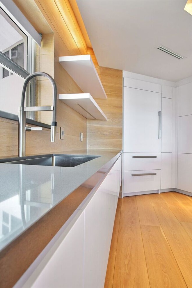 This is an example of an expansive contemporary single-wall open plan kitchen in Miami with open cabinets, white cabinets, beige splashback, stainless steel appliances, light hardwood flooring, an island, a submerged sink, concrete worktops and porcelain splashback.
