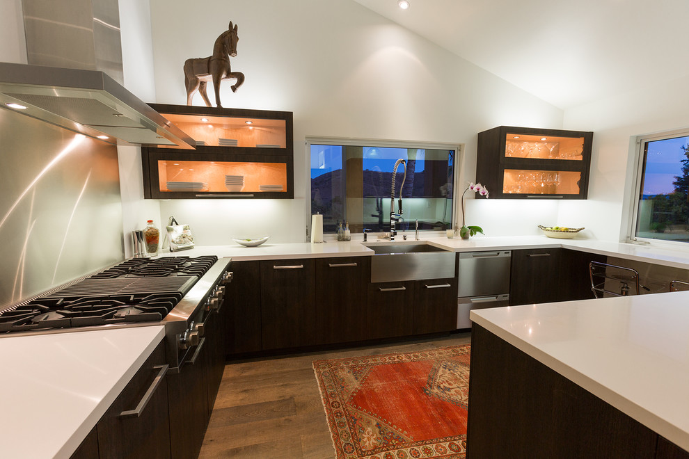 Trendy u-shaped kitchen photo in Los Angeles with a farmhouse sink, flat-panel cabinets, dark wood cabinets, metallic backsplash, metal backsplash and stainless steel appliances