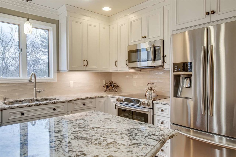 Mid-sized elegant l-shaped light wood floor eat-in kitchen photo in Boston with a single-bowl sink, flat-panel cabinets, white cabinets, granite countertops, beige backsplash, subway tile backsplash, stainless steel appliances, an island and multicolored countertops