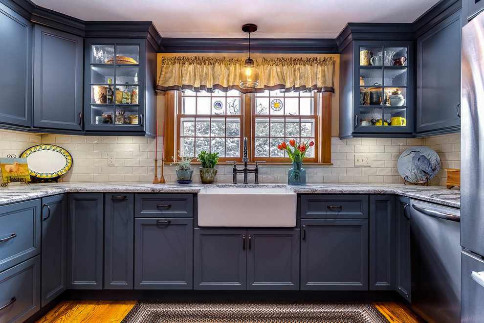 Inspiration for a classic u-shaped kitchen in Bridgeport with a belfast sink, recessed-panel cabinets, blue cabinets, white splashback, metro tiled splashback and medium hardwood flooring.