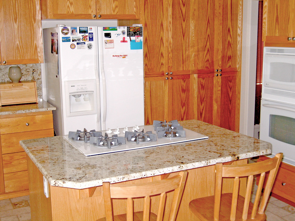 На фото: угловая кухня в классическом стиле с врезной мойкой, фасадами цвета дерева среднего тона, гранитной столешницей и фартуком из каменной плиты