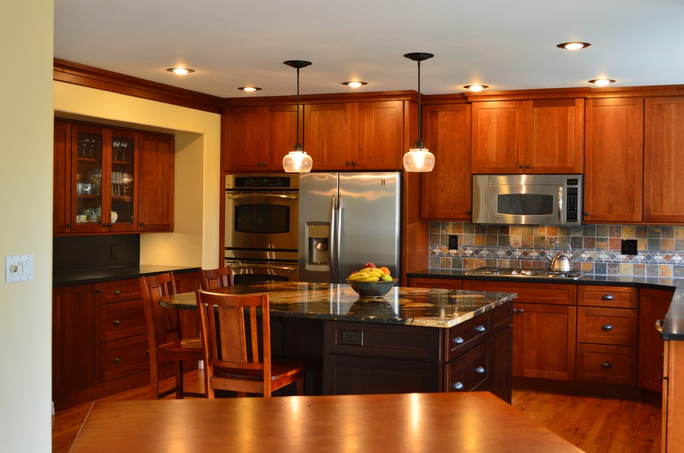 Immagine di una cucina stile americano con lavello sottopiano, ante con riquadro incassato, ante in legno scuro, top in granito, paraspruzzi multicolore, elettrodomestici in acciaio inossidabile e paraspruzzi in ardesia