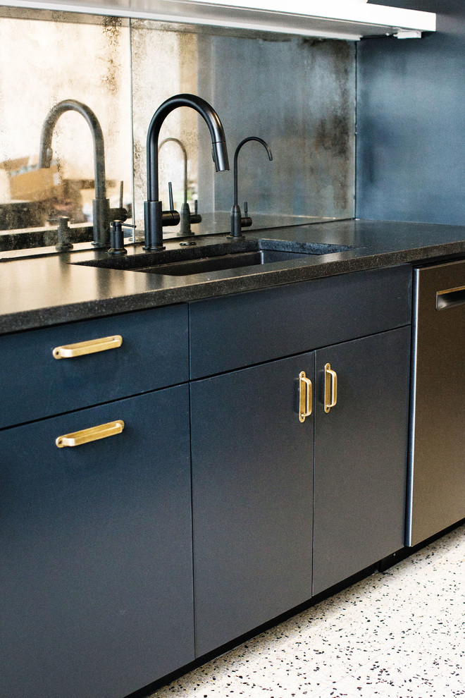 Design ideas for a medium sized industrial single-wall kitchen/diner in Austin with a submerged sink, flat-panel cabinets, blue cabinets, granite worktops, mirror splashback, black appliances, an island and black worktops.