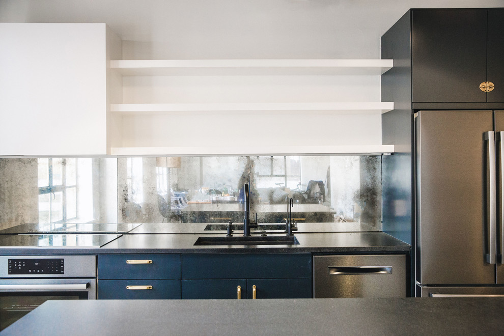 Идея дизайна: прямая кухня среднего размера в стиле лофт с обеденным столом, врезной мойкой, плоскими фасадами, синими фасадами, гранитной столешницей, зеркальным фартуком, черной техникой, островом и черной столешницей