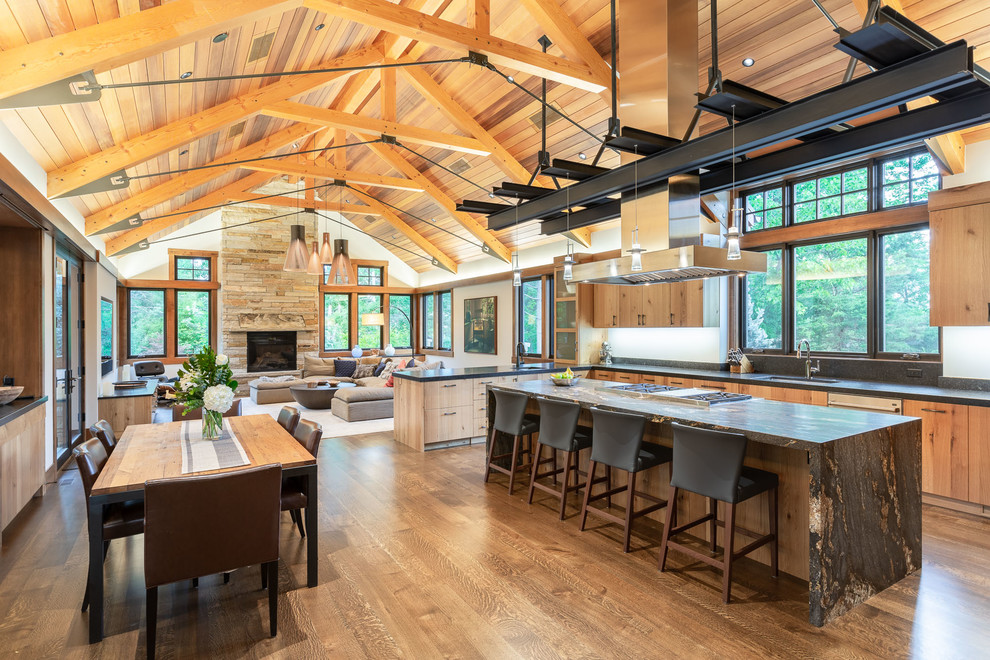 Photo of a rustic open plan kitchen in Denver with flat-panel cabinets, medium wood cabinets, stainless steel appliances, medium hardwood flooring, an island, brown floors and grey worktops.