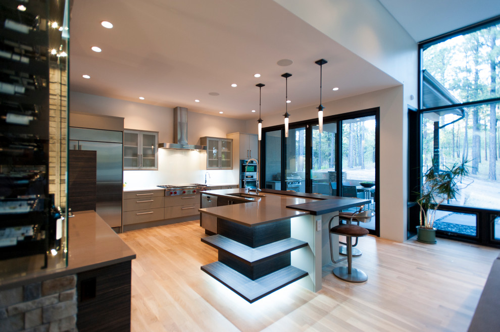 This is an example of a large contemporary l-shaped open plan kitchen in Denver with a submerged sink, flat-panel cabinets, grey cabinets, engineered stone countertops, stainless steel appliances, light hardwood flooring, an island and beige floors.