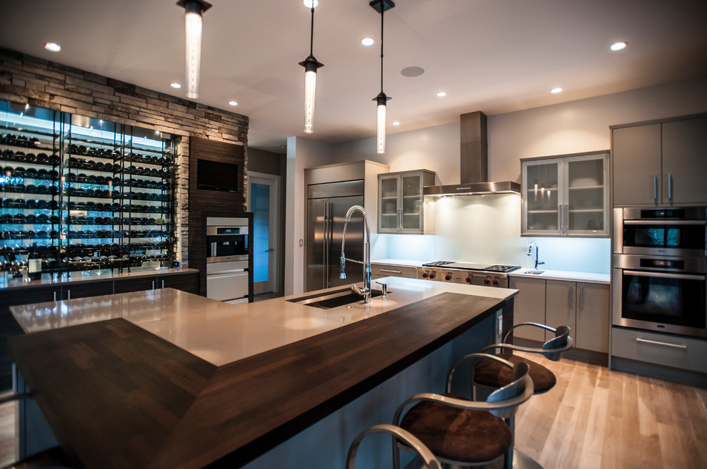 This is an example of a large contemporary l-shaped open plan kitchen in Denver with a submerged sink, flat-panel cabinets, grey cabinets, engineered stone countertops, stainless steel appliances, light hardwood flooring, an island and beige floors.