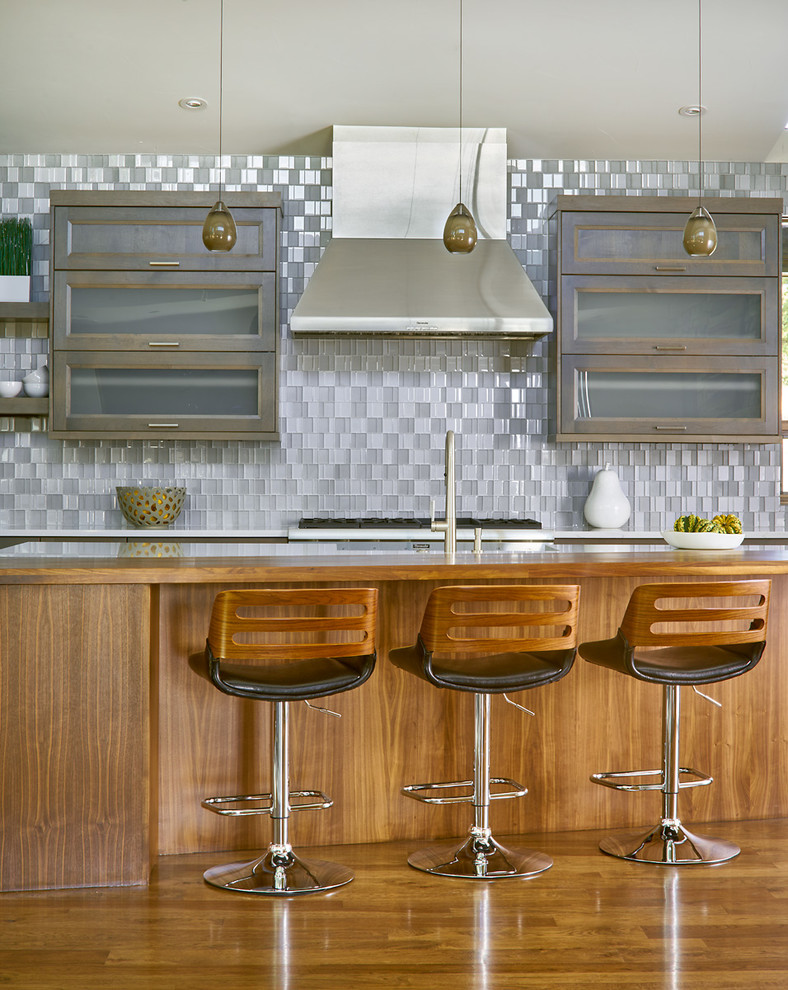 Inredning av ett modernt mellanstort linjärt kök med öppen planlösning, med en rustik diskho, luckor med glaspanel, grått stänkskydd, rostfria vitvaror, mellanmörkt trägolv och flera köksöar