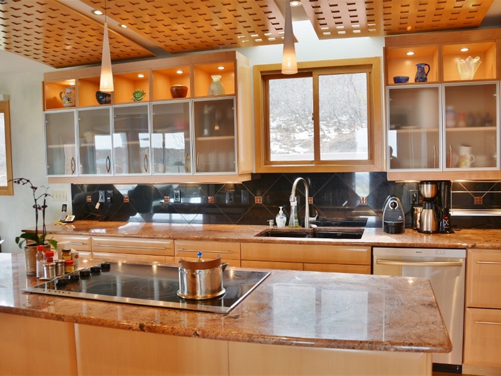 Foto di una grande cucina design con lavello sottopiano, ante lisce, ante in legno chiaro, top in granito, paraspruzzi nero, paraspruzzi con piastrelle di vetro, elettrodomestici in acciaio inossidabile e parquet chiaro