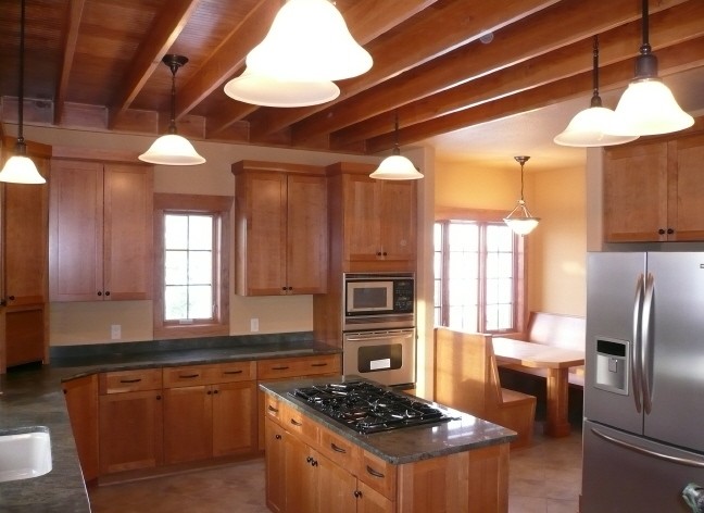 Inspiration for a mid-sized craftsman u-shaped ceramic tile enclosed kitchen remodel in Denver with an undermount sink, shaker cabinets, dark wood cabinets, granite countertops, stainless steel appliances and an island
