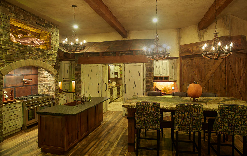 Example of a large mountain style galley eat-in kitchen design in Denver with raised-panel cabinets, distressed cabinets, soapstone countertops, beige backsplash and an island