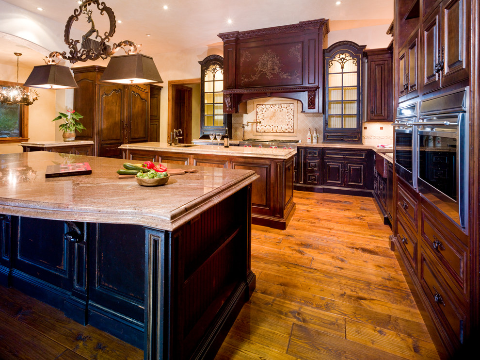 Bild på ett stort vintage kök, med en rustik diskho, luckor med upphöjd panel, skåp i mellenmörkt trä, granitbänkskiva, beige stänkskydd, stänkskydd i stenkakel, rostfria vitvaror, mellanmörkt trägolv, flera köksöar och brunt golv