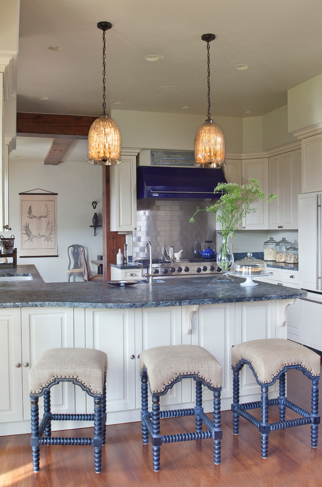 Rustik inredning av ett avskilt, mellanstort blå blått kök, med en undermonterad diskho, bänkskiva i täljsten, stänkskydd med metallisk yta, stänkskydd i metallkakel, integrerade vitvaror, mörkt trägolv, en halv köksö, luckor med upphöjd panel och beige skåp