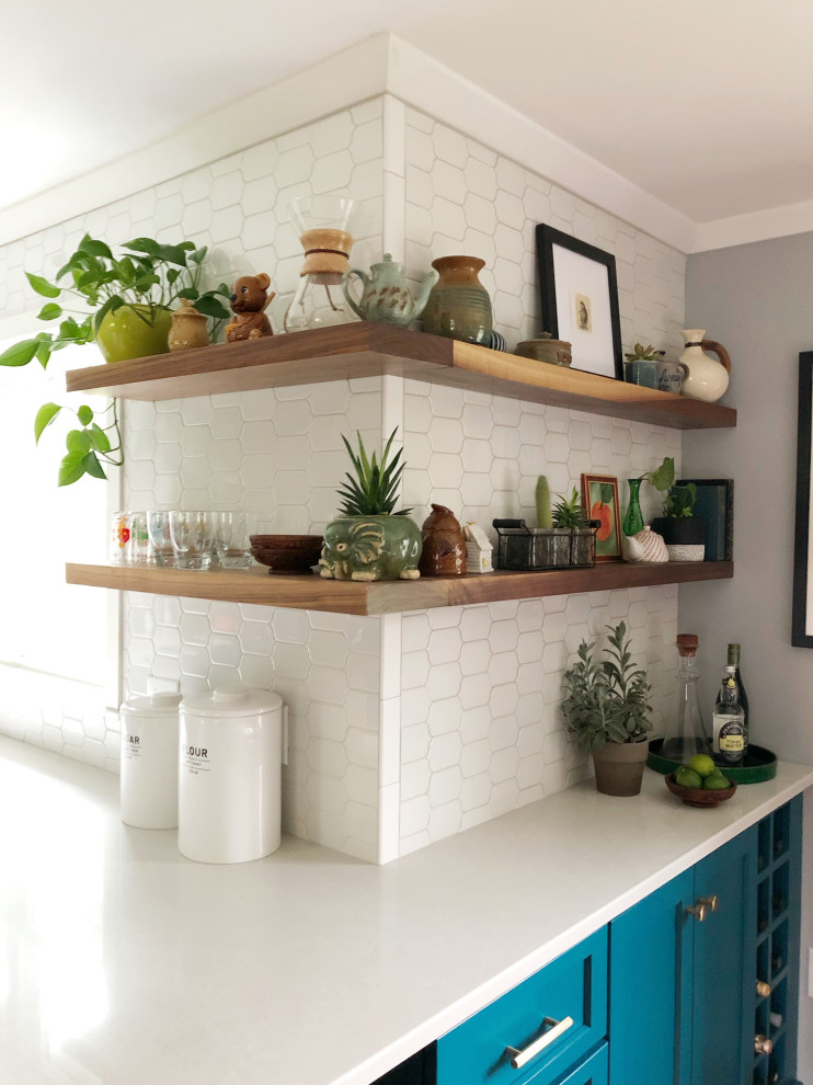 Inspiration for a medium sized eclectic galley open plan kitchen in Other with a belfast sink, shaker cabinets, white cabinets, engineered stone countertops, white splashback, mosaic tiled splashback, stainless steel appliances, porcelain flooring, a breakfast bar, grey floors and white worktops.