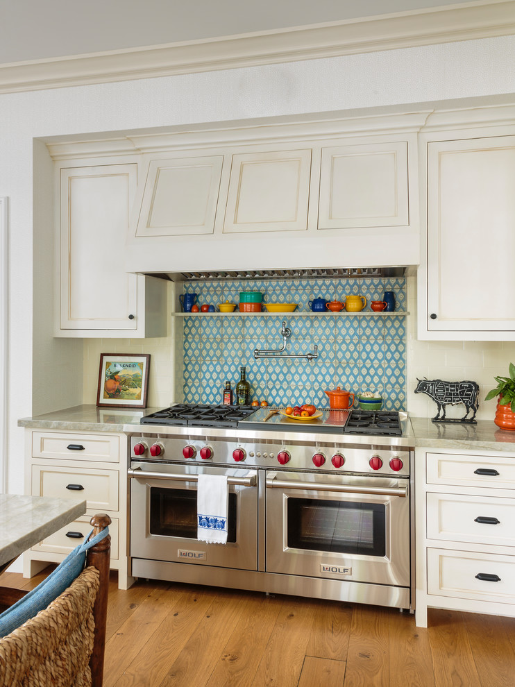 Inredning av ett lantligt stort grå grått kök med öppen planlösning, med en rustik diskho, luckor med infälld panel, grå skåp, bänkskiva i kvartsit, vitt stänkskydd, stänkskydd i keramik, rostfria vitvaror, ljust trägolv, en köksö och brunt golv