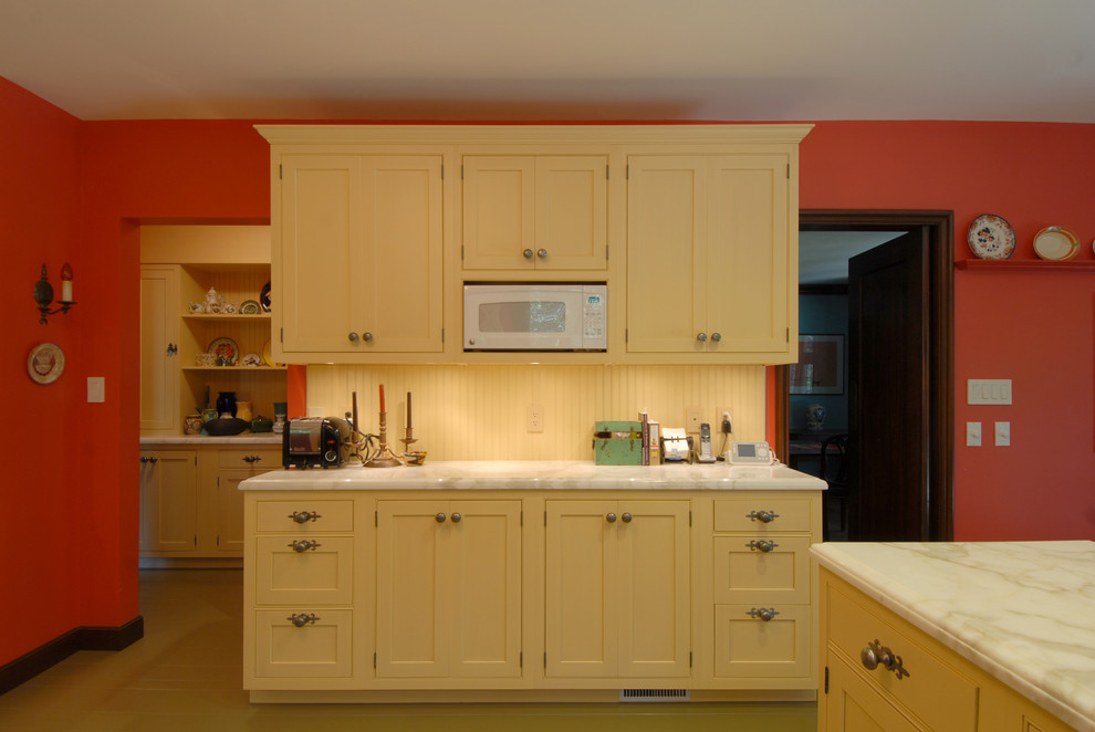 Inspiration för avskilda, mellanstora eklektiska l-kök, med en undermonterad diskho, skåp i shakerstil, gula skåp, marmorbänkskiva, gult stänkskydd, stänkskydd i trä, rostfria vitvaror, målat trägolv, en halv köksö och beiget golv