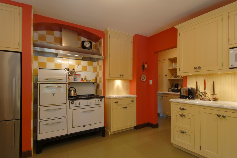 Photo of a medium sized bohemian l-shaped enclosed kitchen in San Francisco with white appliances, yellow cabinets, a submerged sink, shaker cabinets, marble worktops, yellow splashback, wood splashback, painted wood flooring, a breakfast bar and beige floors.