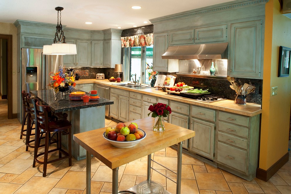 Inspiration for a large eclectic u-shaped ceramic tile open concept kitchen remodel in Cleveland with a double-bowl sink, raised-panel cabinets, blue cabinets, tile countertops, blue backsplash, stone tile backsplash, stainless steel appliances and an island
