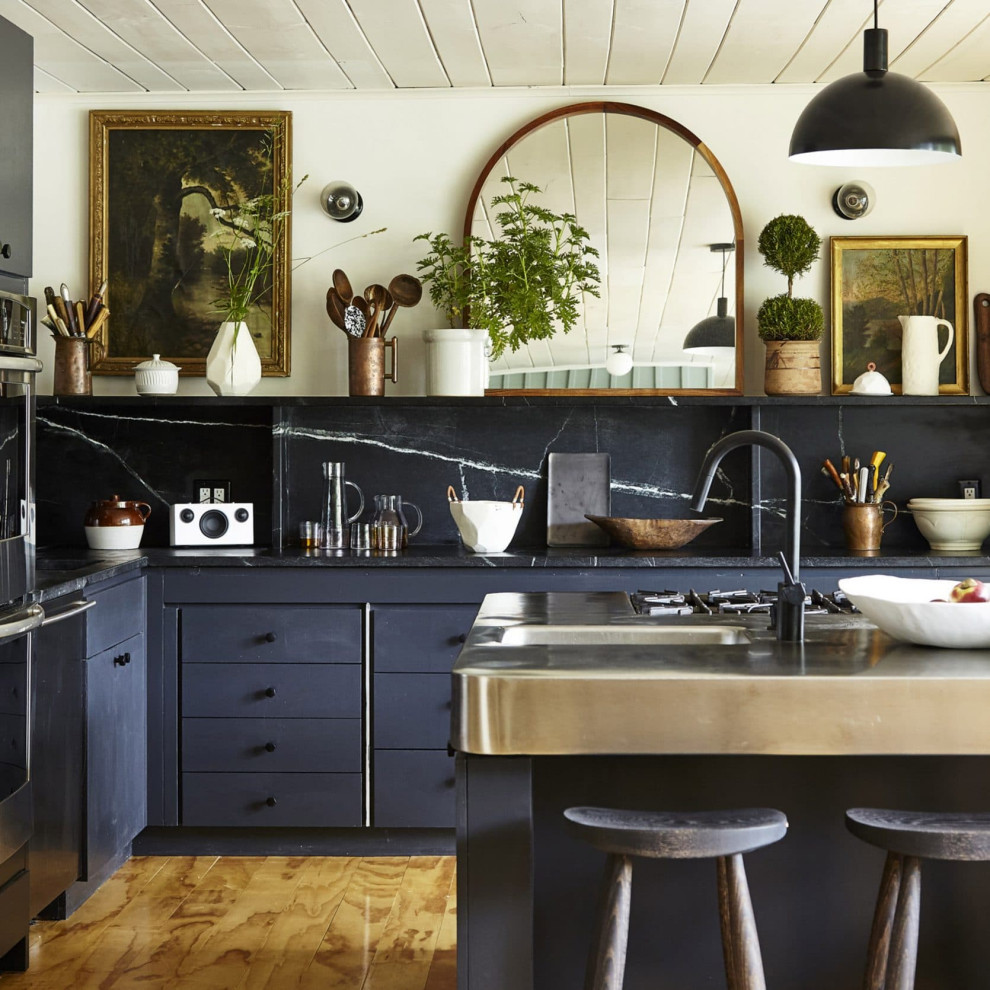 Klassische Küche in L-Form mit integriertem Waschbecken, flächenbündigen Schrankfronten, blauen Schränken, Edelstahl-Arbeitsplatte, Küchenrückwand in Schwarz, Rückwand aus Stein, braunem Holzboden und Kücheninsel in Boston