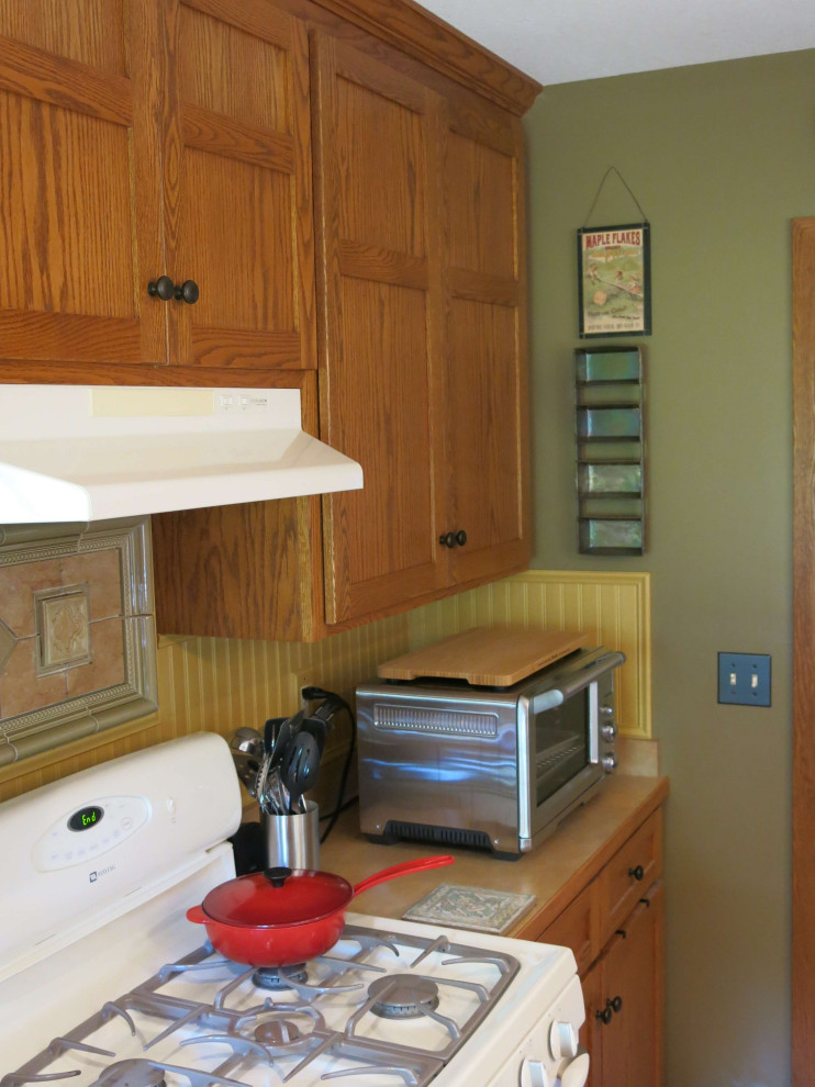 Aménagement d'une cuisine américaine en bois brun avec un évier posé, un placard à porte plane, un plan de travail en stratifié, une crédence jaune, un sol en bois brun et îlot.
