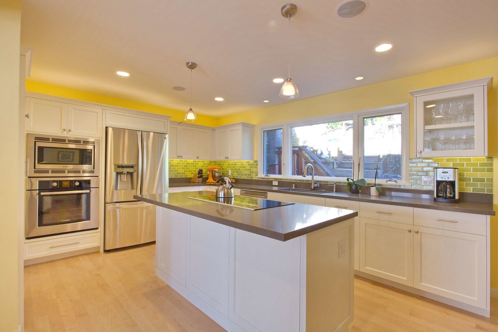 Foto på ett stort funkis kök, med en undermonterad diskho, släta luckor, vita skåp, bänkskiva i kvarts, grönt stänkskydd, stänkskydd i keramik, rostfria vitvaror, ljust trägolv, en köksö och beiget golv