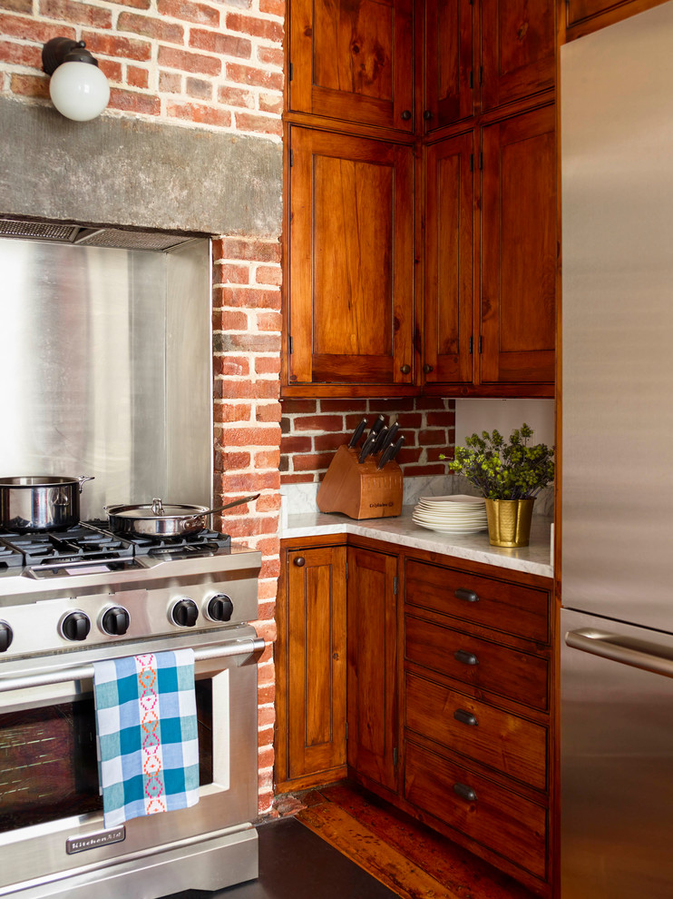 Inspiration pour une cuisine parallèle victorienne de taille moyenne avec un placard à porte shaker, plan de travail en marbre, une crédence en brique, un électroménager en acier inoxydable, un sol en bois brun et un sol marron.
