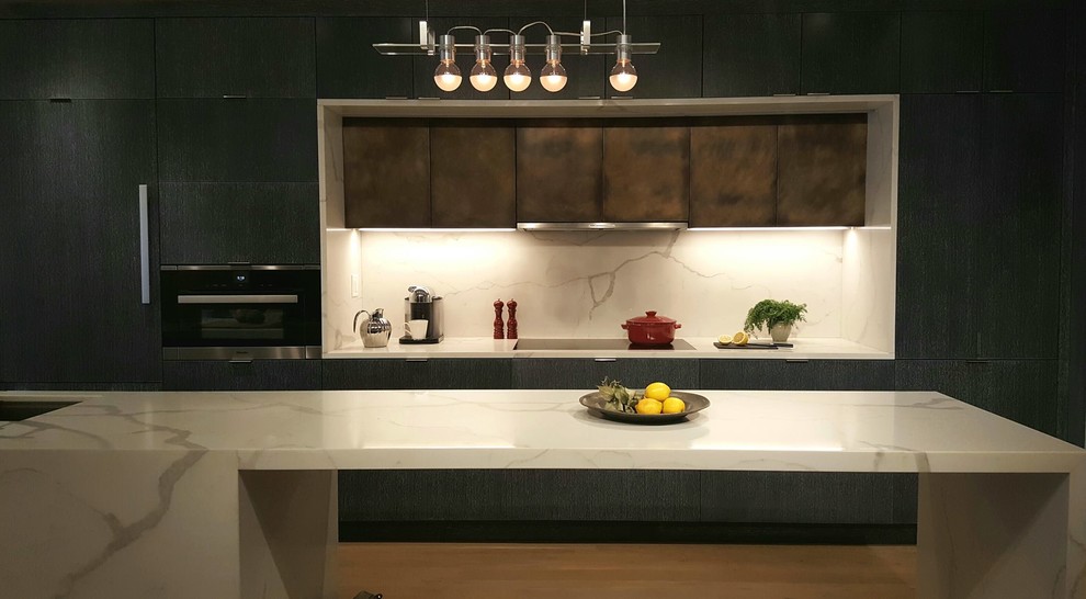 Bild på ett funkis kök, med en undermonterad diskho, släta luckor, skåp i mörkt trä, bänkskiva i kvarts, rostfria vitvaror, en köksö, ljust trägolv och stänkskydd i sten