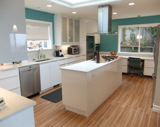 Design ideas for a medium sized contemporary u-shaped enclosed kitchen in San Diego with a submerged sink, engineered stone countertops, white splashback, stainless steel appliances, an island, flat-panel cabinets and white cabinets.