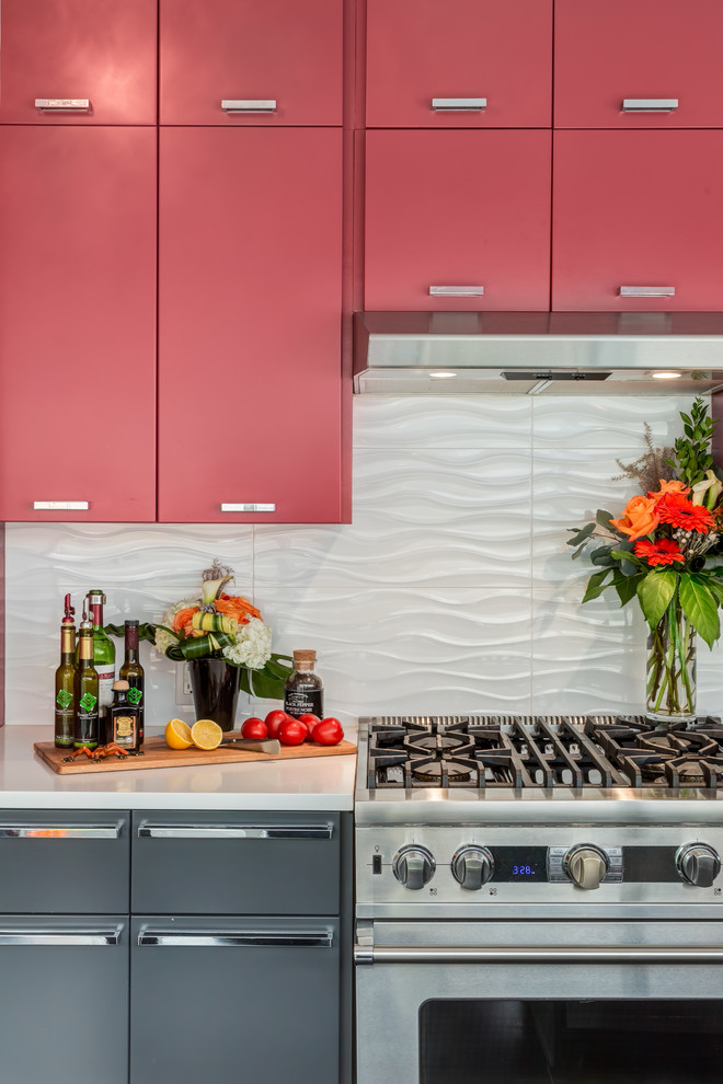 This is an example of a medium sized modern enclosed kitchen in Calgary with white splashback, porcelain splashback, stainless steel appliances, an island, a submerged sink, flat-panel cabinets, red cabinets, engineered stone countertops and porcelain flooring.