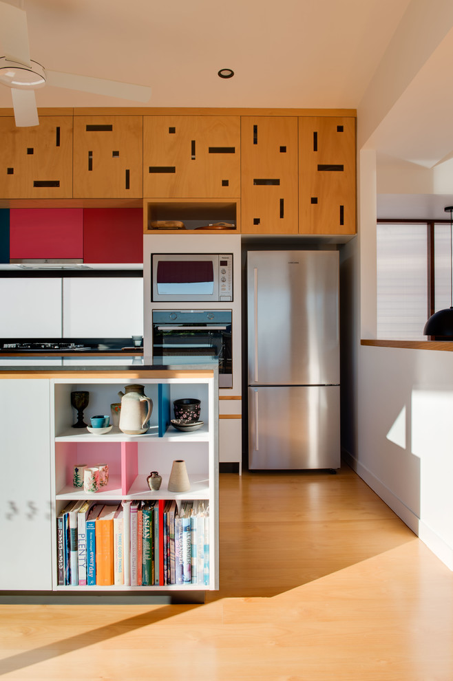 Exempel på ett mellanstort modernt kök, med skåp i ljust trä, fönster som stänkskydd, svarta vitvaror, ljust trägolv och en köksö