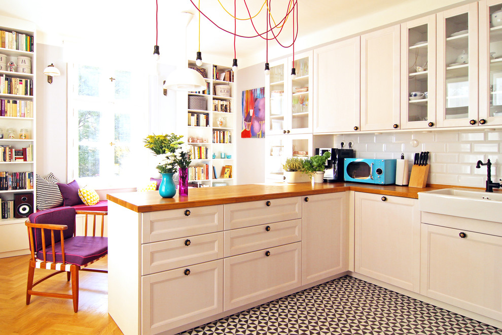 Foto på ett mellanstort eklektiskt kök, med en rustik diskho, luckor med infälld panel, vita skåp, träbänkskiva, vitt stänkskydd, stänkskydd i tunnelbanekakel, svarta vitvaror, klinkergolv i keramik och en halv köksö