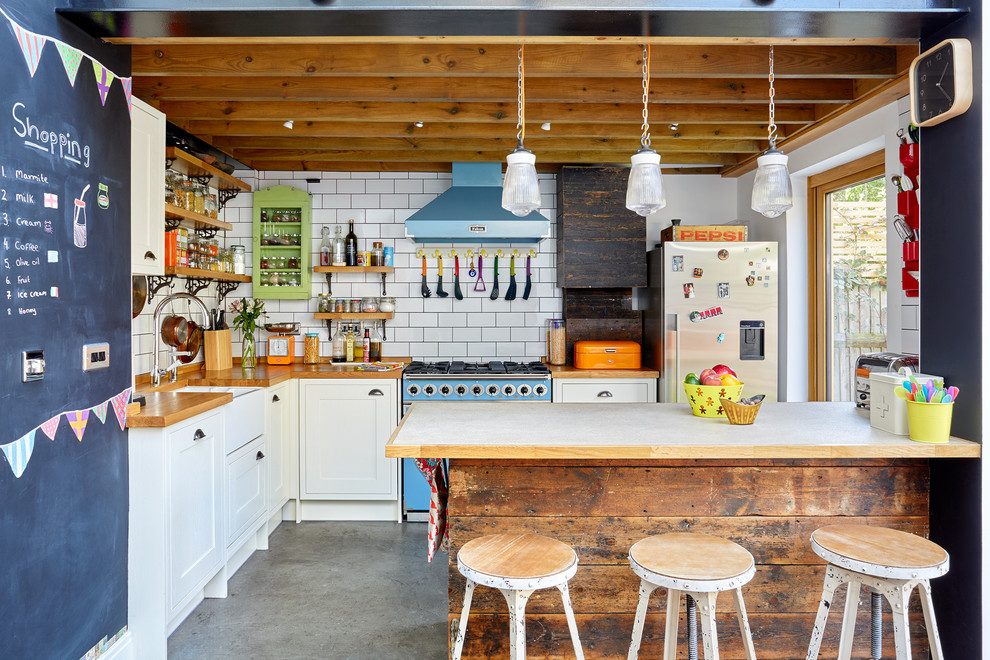 Ejemplo de cocinas en L bohemia de tamaño medio abierta con fregadero sobremueble, armarios estilo shaker, puertas de armario blancas, encimera de madera, salpicadero blanco, electrodomésticos de colores, suelo de cemento, una isla, salpicadero de azulejos tipo metro y barras de cocina