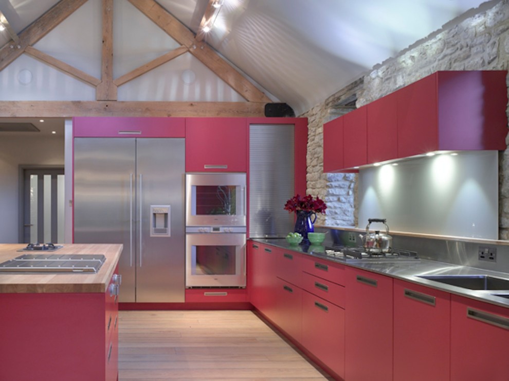 Foto på ett stort funkis kök med öppen planlösning, med en undermonterad diskho, släta luckor, röda skåp, bänkskiva i rostfritt stål, stänkskydd med metallisk yta, rostfria vitvaror och en köksö