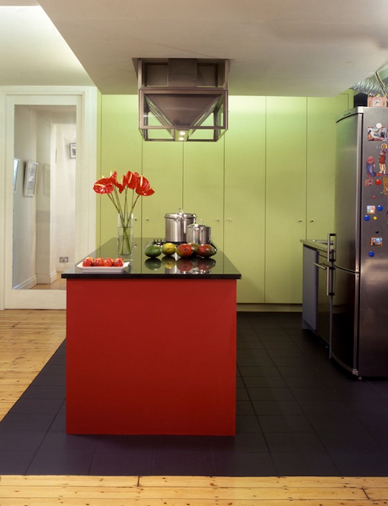 Large contemporary open plan kitchen in London with flat-panel cabinets, red cabinets, granite worktops, stainless steel appliances and an island.