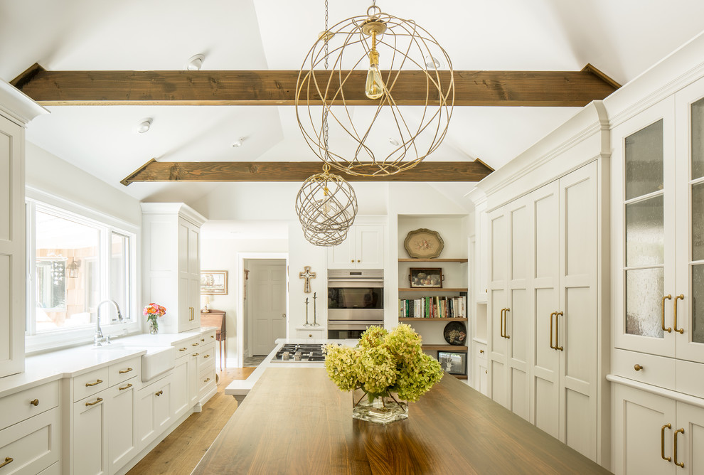 Kitchen - large country u-shaped medium tone wood floor kitchen idea in New York with shaker cabinets, white cabinets, a farmhouse sink, quartz countertops, stainless steel appliances and an island