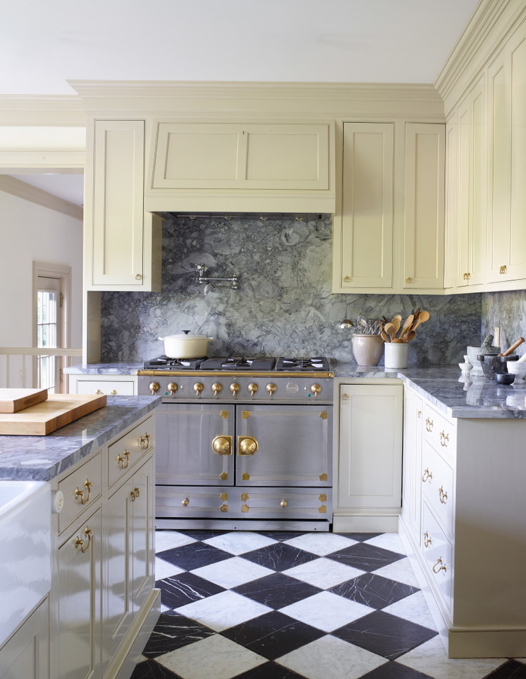 Photo of a farmhouse kitchen in New York with a belfast sink, shaker cabinets, yellow cabinets, grey splashback, stainless steel appliances and an island.