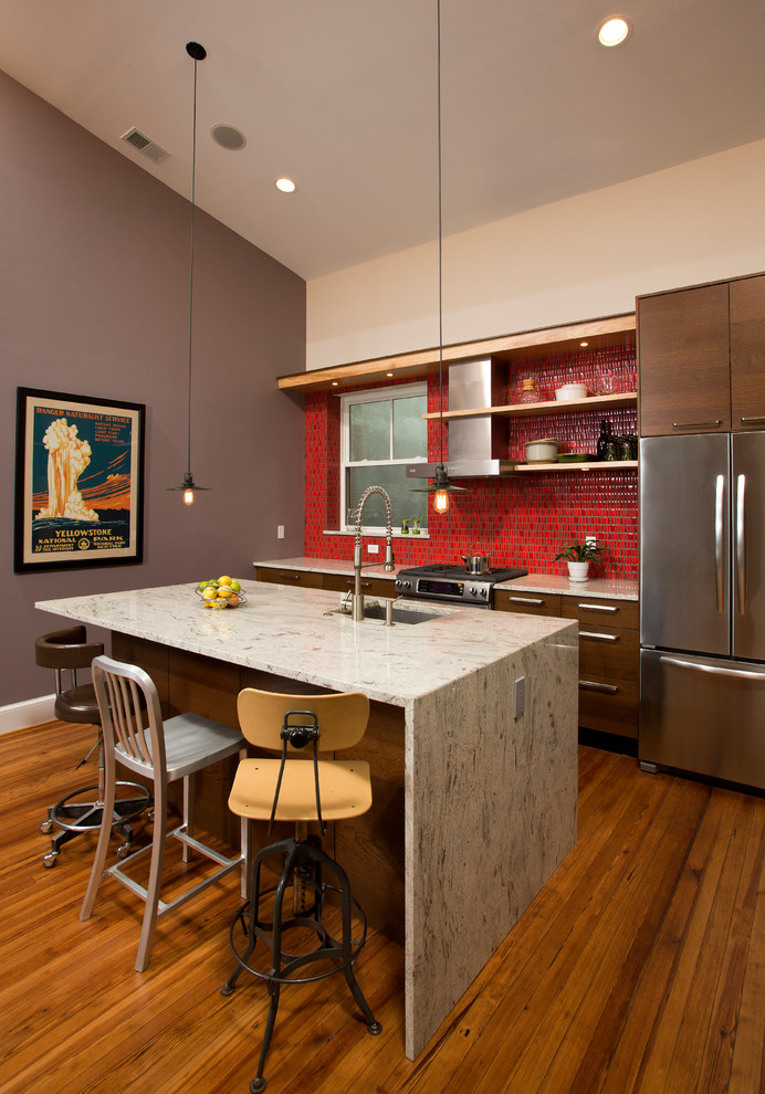 Foto på ett mellanstort funkis linjärt kök och matrum, med en enkel diskho, släta luckor, bruna skåp, granitbänkskiva, rött stänkskydd, stänkskydd i porslinskakel, rostfria vitvaror, mellanmörkt trägolv och en köksö